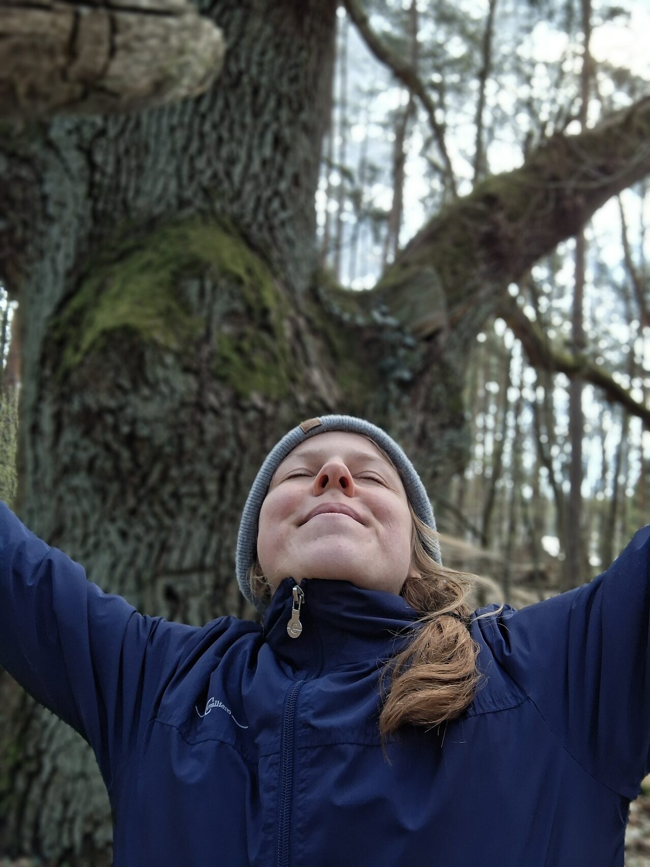 Christin Reimann hat die Augen geschlossen und genießt die Waldatmosphäre. Ihre Arme sind seitlich nach oben gestreckt.